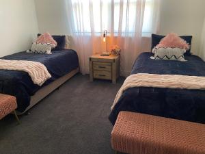 a bedroom with two beds and a table with a lamp at Gem On Jamieson in Broken Hill