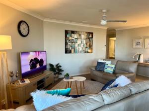 a living room with a couch and a flat screen tv at Heritage unit 101 in Tuncurry