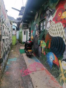 una pared cubierta de graffiti con una motocicleta estacionada al lado en Hostal Gastro Bar Casa Colibrí, en Bogotá