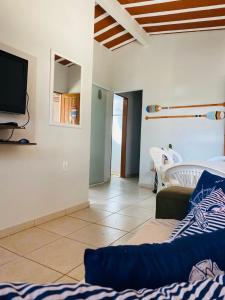 a living room with a couch and a tv at MAR DOCE LAR - Praia de Sossego in São Francisco de Itabapoana