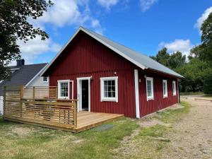 Ljungbyhed的住宿－Holiday home Ljungbyhed II，一个带门廊和甲板的红色谷仓