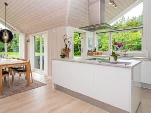 a kitchen with white cabinets and a dining room with a table at 6 person holiday home in Oksbøl-By Traum in Oksbøl