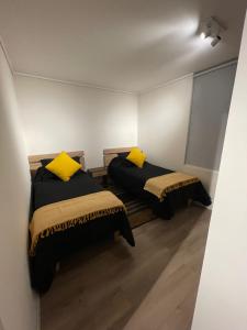two beds with yellow pillows in a room at Hermoso departamento Reñaca con Piscina in Viña del Mar