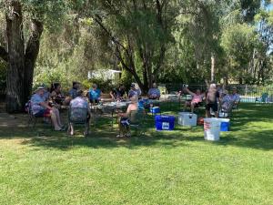 grupa ludzi siedzących przy stole piknikowym w parku w obiekcie Fairway Views Motor Inn w mieście Tocumwal