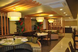 a restaurant with tables and chairs and chandeliers at Hotel Green Olive in Aurangabad