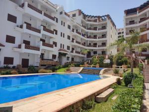 un appartement avec une piscine en face d'un bâtiment dans l'établissement Residence Al Kasaba - Spacious apartment with swimming pool and direct access to sea, à Oued Laou