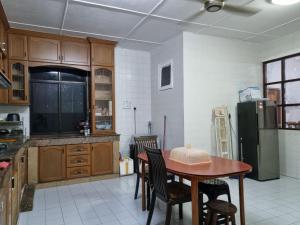 a kitchen with a table and chairs and a refrigerator at Kenyalang Lutong Homestay in Miri