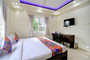 a bedroom with a bed and a desk and a window at FabHotel Anchorage Inn in Kolkata