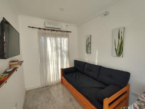 sala de estar con sofá negro y TV en Atardecer Serrano en Sierra de la Ventana