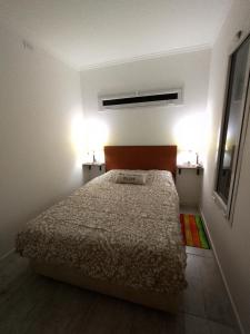a bedroom with a bed and two lights on the wall at Atardecer Serrano in Sierra de la Ventana