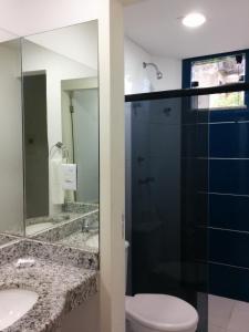 a bathroom with a toilet and a glass shower at Hotel Mundial in Itabuna