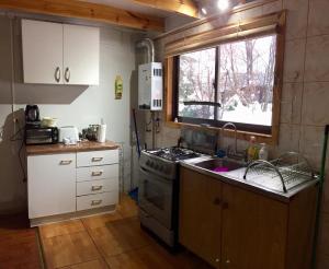a kitchen with a stove and a sink and a window at Villa La Quimera in Nevados de Chillan