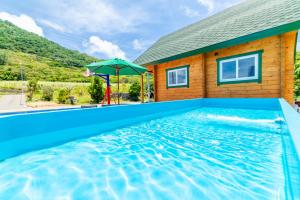 uma casa com piscina e guarda-sol em レジーナ石垣　ログテリアⅠ em Hirakubo