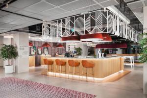 a lobby with a bar with orange stools at Rove Expo City in Dubai +20 photos