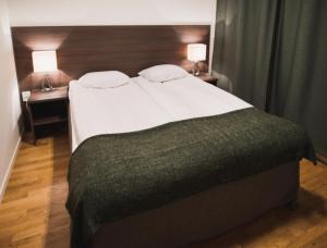 斯德哥爾摩的住宿－希斯塔愛克斯查酒店，卧室内的一张大床,配有两张桌子和两盏灯