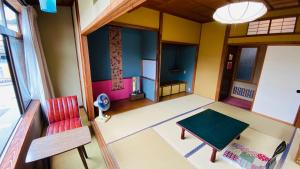 sala de estar con silla roja y mesa en ゲストハウス　華屋 (guest house HANAYA）, en Sado