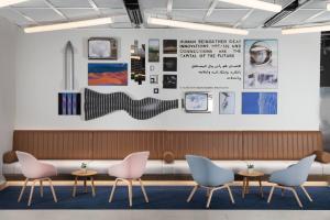a waiting room with pink chairs and a white wall at Rove Expo City in Dubai