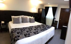 1 dormitorio con 1 cama grande y edredón blanco y negro en Hotel Boutique Feria Internacional, en Bogotá