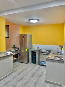 una cocina con paredes amarillas y electrodomésticos de acero inoxidable en Suites Hermosas cercanas a todo, en Puerto Ayora