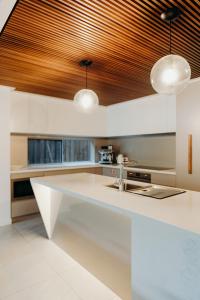 a kitchen with white counters and a wooden ceiling at KoKos Beach House 3 in Byron Bay