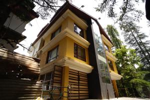 a yellow and black house with stairs and trees at Mahaveer Shimla By Royal Collection Hotels in Shimla