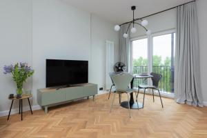 - un salon avec une télévision et une table avec des chaises dans l'établissement Warszawa Bohema Szwedzka Apartment by Renters, à Varsovie