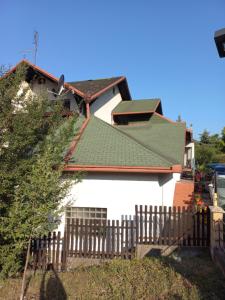una casa con techo verde y valla en Apartments Emir, en Tuzla