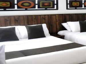Habitación con 2 camas blancas y paredes de madera. en Hotel Boutique Embajada de la Feria, en Bogotá