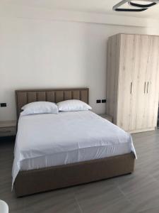 - une chambre avec un grand lit et une armoire en bois dans l'établissement Sunset Luxury Studios, à Radhimë