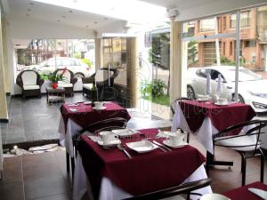 a restaurant with two tables with red and white table settings at Hotel Boutique Embajada de la Feria in Bogotá