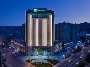 un bâtiment éclairé dans une ville la nuit dans l'établissement Holiday Inn Xining Datong, an IHG Hotel, à Xining