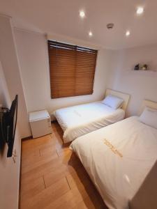 two beds in a room with a window at Moon Sun Guesthouse in Seoul