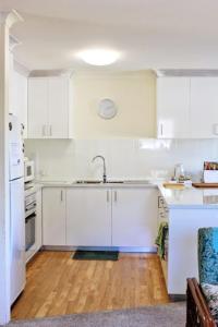 a kitchen with white cabinets and a wooden floor at Sanctuary Court Unit 4 in Gold Coast