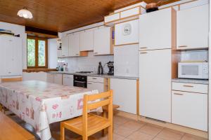 a kitchen with white cabinets and a table with a chair at Les Mouflons in La Chapelle-dʼAbondance
