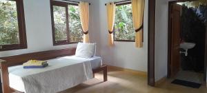 a bedroom with a bed and two windows at Giri Carik in Sidemen