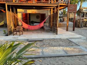 een patio met een hangmat voor een huis bij BEACH HOUSE - Suite 2 - NA PRAIA -BEACHFRONT in Barra Grande