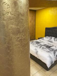 a bedroom with a bed and a yellow wall at Jacuzzi Apartament Old town in Klaipėda