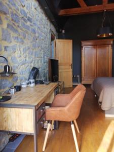 a bedroom with a stone wall and a desk and a bed at La LAITERIE Ecaussinnes in Les Croisettes