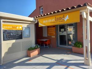 un restaurante con un letrero que lee tierra de vacaciones en HOLIDAYLAND BAIE DES OLIVIERS VILLA 36m2 1chambre fermée 6 couchages ou VILLA 41M2 2chambres fermées 7 couchages, en Narbonne-Plage