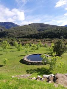 einen Teich auf einem Feld mit Bergen im Hintergrund in der Unterkunft Die Skoolhuisie 