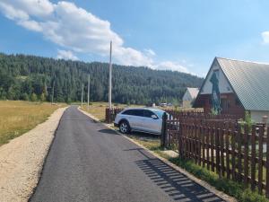um carro estacionado ao lado de uma cerca numa estrada em Family home Miković em Žabljak