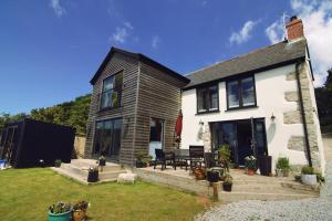a white house with a picnic table in the yard at Luxurious property set in the heart of Cornwall with breathtaking views -Rhubarb Cottage in Helston