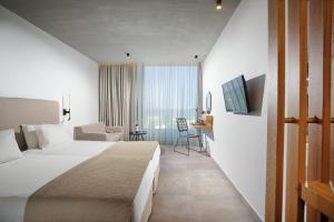 ein Hotelzimmer mit einem großen Bett und einem Schreibtisch in der Unterkunft Caravia Beach Hotel in Marmari