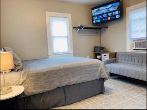 a bedroom with a bed and a couch and a flat screen tv at CHERRY ST LITTLE LOVE HOUSE* SHOP*DINE* RT 66*EXPO CENTER*BOK*DOWNTOWN in Tulsa