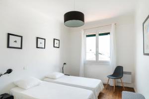 une chambre avec deux lits et une chaise dans l'établissement Appartement Saint-jean-de-luz, à Saint-Jean-de-Luz