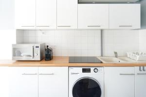 une cuisine blanche avec une machine à laver et un micro-ondes dans l'établissement Appartement Saint-jean-de-luz, à Saint-Jean-de-Luz 16 autres photos