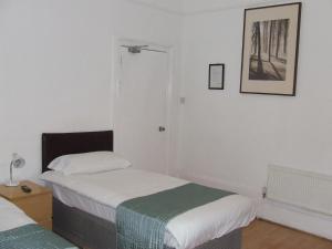 a bedroom with two beds and a picture on the wall at Cedars House Hotel in Croydon