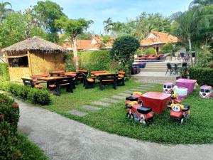 einen Garten mit Tischen und Spielzeugzügen im Gras in der Unterkunft Boonya Resort Koh Chang in Ko Chang