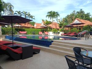 einen Pool mit Stühlen, Tischen und einem Sonnenschirm in der Unterkunft Boonya Resort Koh Chang in Ko Chang