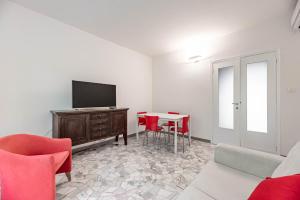 een woonkamer met een tv en een tafel met stoelen bij Appartamento sul fiume al Portello in Padua